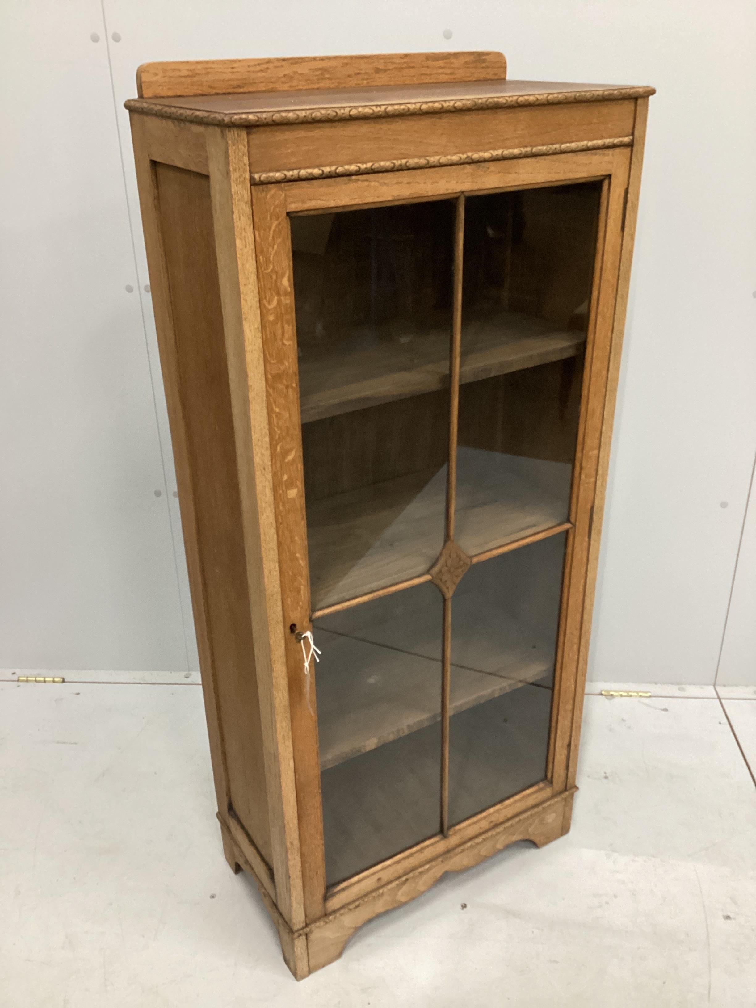 An early 20th century glazed oak narrow bookcase, width 58cm, depth 29cm, height 130cm